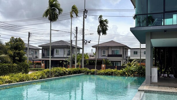 Una piscina con agua cristalina, rodeada por un edificio moderno y casas residenciales.