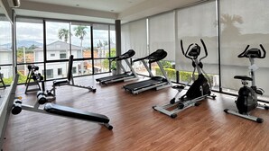 Un gimnasio moderno con equipo de ejercicio, ventanas amplias y piso de madera.