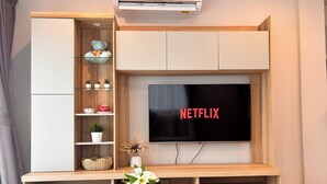 Una sala de estar moderna con televisor empotrado, estanterías de madera y una pequeña mesa con un jarrón de flores.