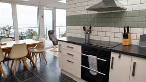 Een moderne keuken met een zwart aanrecht, witte kasten en uitzicht naar buiten.