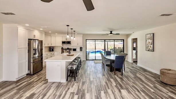 A modern kitchen with a central island, stainless steel appliances, and a dining area with a view.