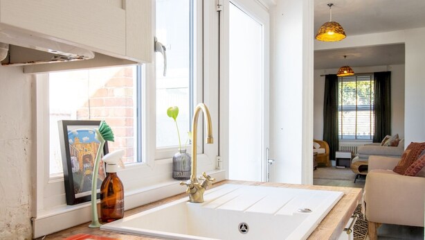 A modern kitchen with a large white sink, a framed picture of a street scene, and a bottle of Purina dog food on the counter. - Pass the Keys | Townhouse in Rye, East Sussex, near Camber Sands (Rye)