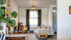 A cozy living room with a sofa, a coffee table, and a dining table. There is a window with curtains, a hanging light fixture, and a plant. - Pass the Keys | Townhouse in Rye, East Sussex, near Camber Sands (Rye)