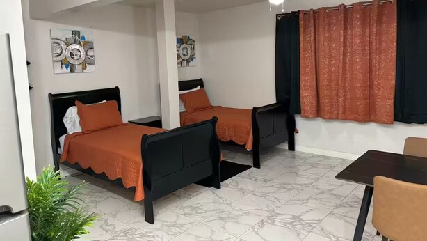 Habitación de hotel con dos camas, una mesa de comedor y un ventilador de techo.