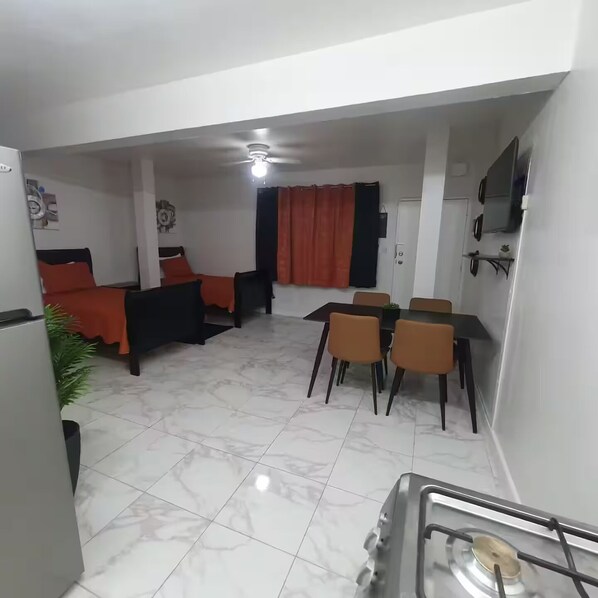 A compact living space with a bed, a dining area, and a kitchenette.