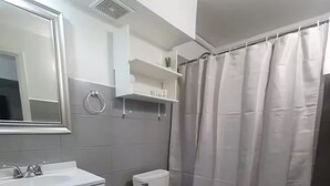 Un baño con inodoro, lavamanos y cortina de ducha.
