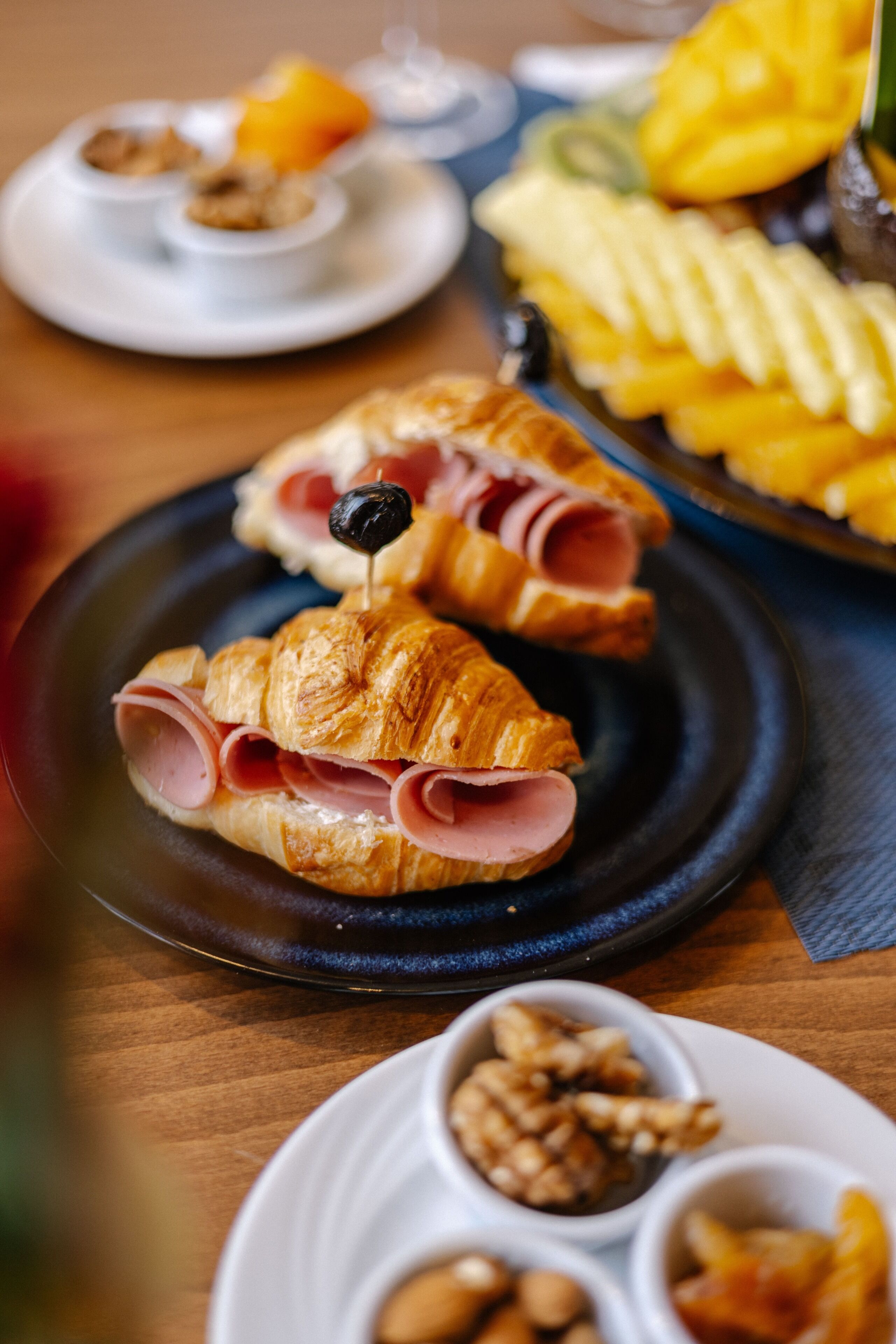 A table with croissants, a plate of fruit, and a plate of nuts.