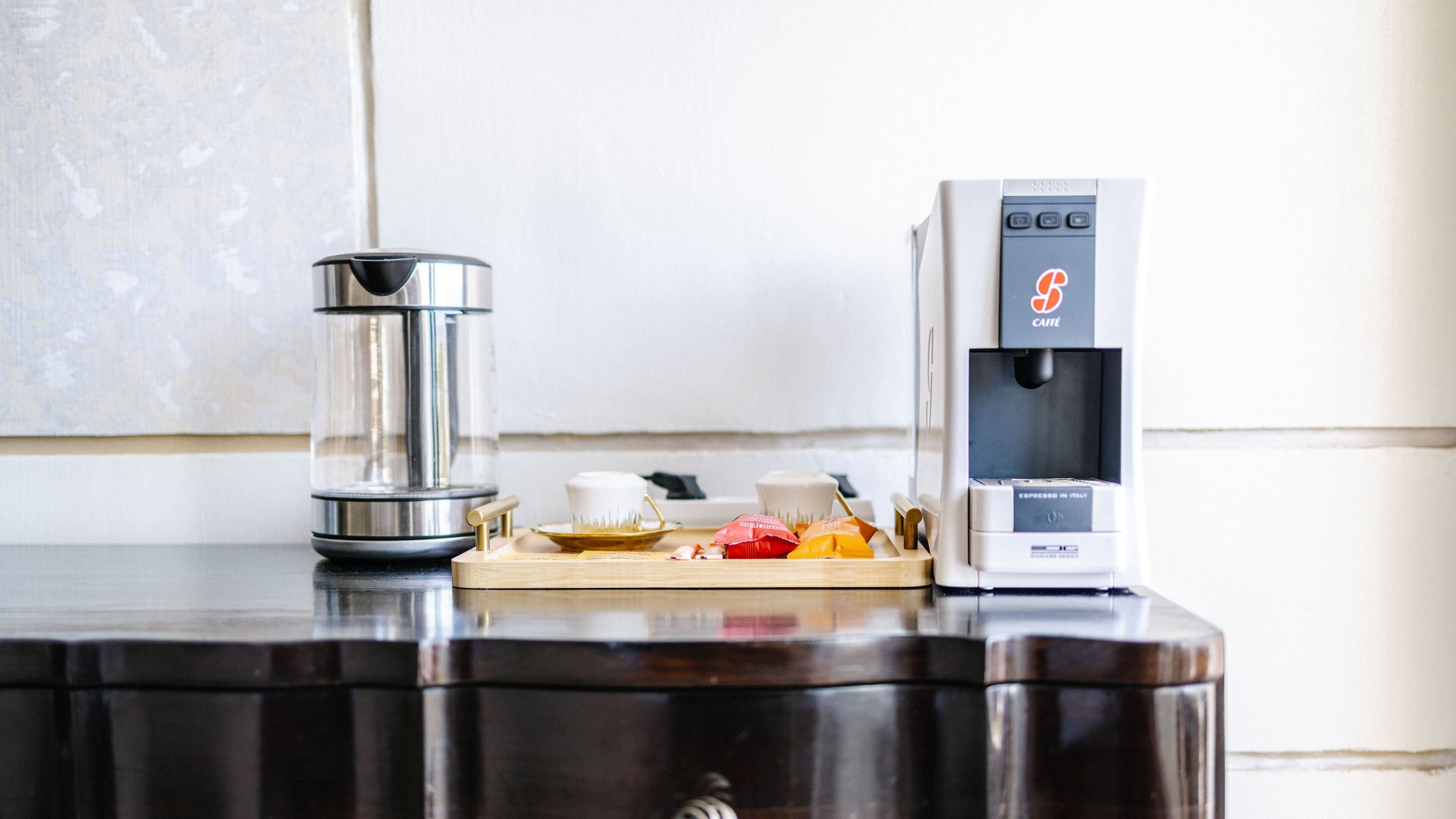 Eine Kaffeemaschine und eine Glas-Kaffeekanne auf einem Holztisch mit einer Snackplatte.