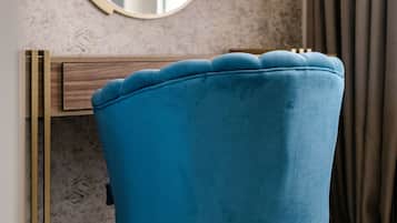 A blue chair with wooden legs and a round mirror on a wall with a textured pattern.