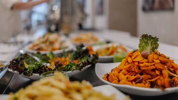 A buffet table with various dishes including a pile of sliced carrots and a salad with lettuce.