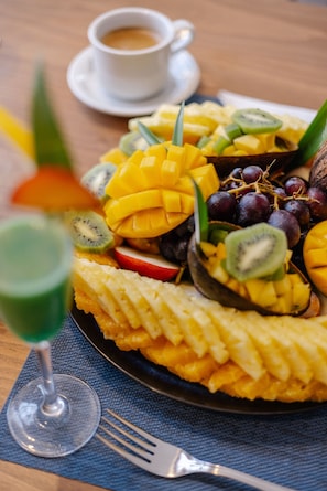 A fruit platter with sliced mangoes, kiwis, and grapes on a plate. - Hotel Prestige Agadir (Agadir)
