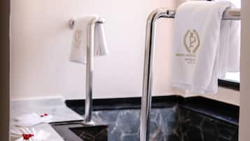 Une salle de bain avec un sol en marbre, un porte-serviettes avec une serviette, et une paire de chaussons ornés d’un nœud rouge.