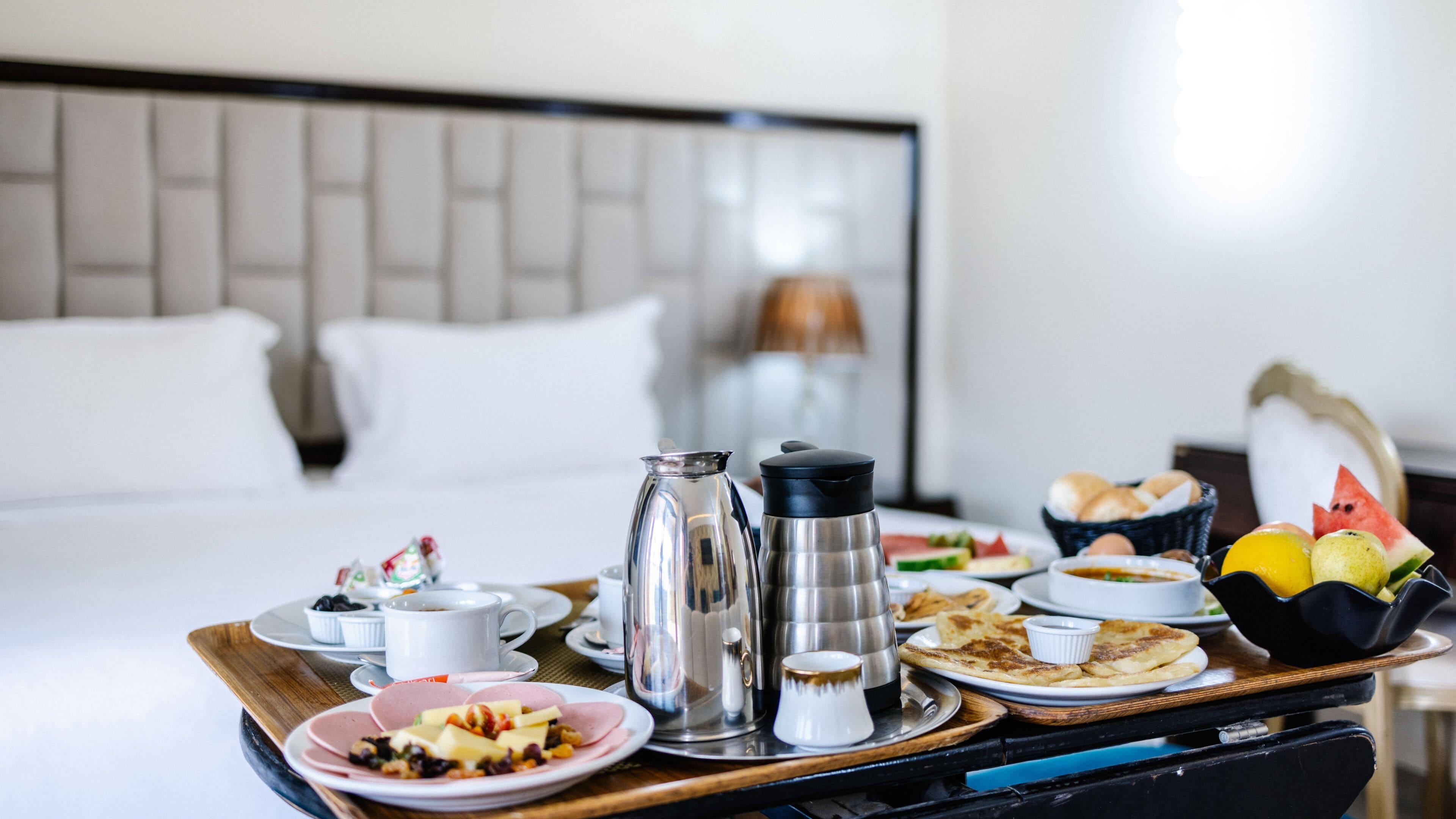 A breakfast tray with coffee, pastries, and fruits on a hotel room table.