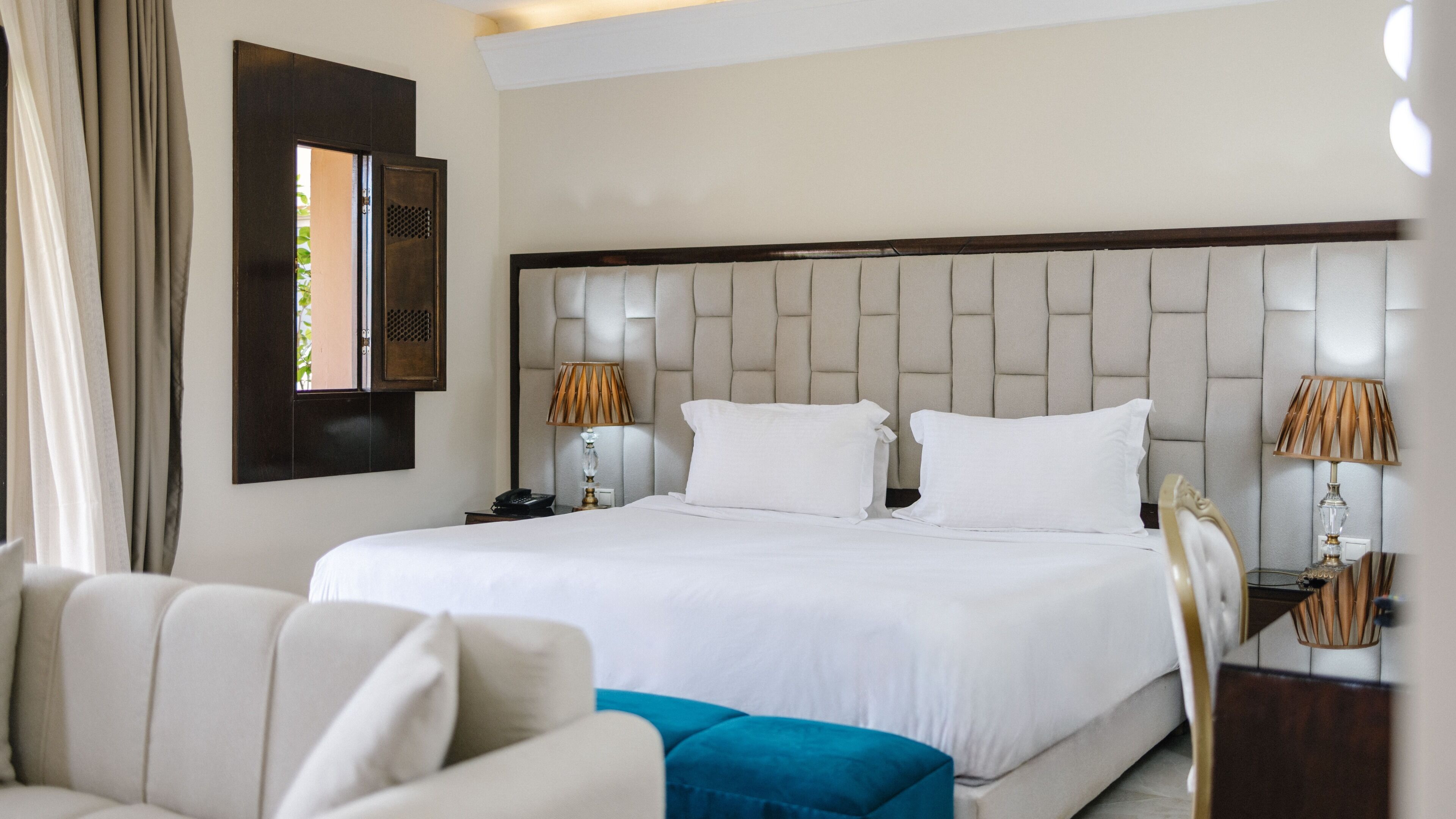 Una habitación de hotel con una cama grande, dos mesitas de noche, una silla y un espejo en la pared.
