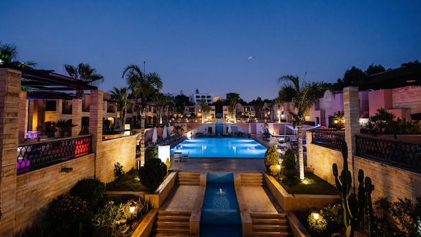 A nighttime view of a resort with a central swimming pool, palm trees, and a well-lit building facade. - Hotel Prestige Agadir (Agadir)