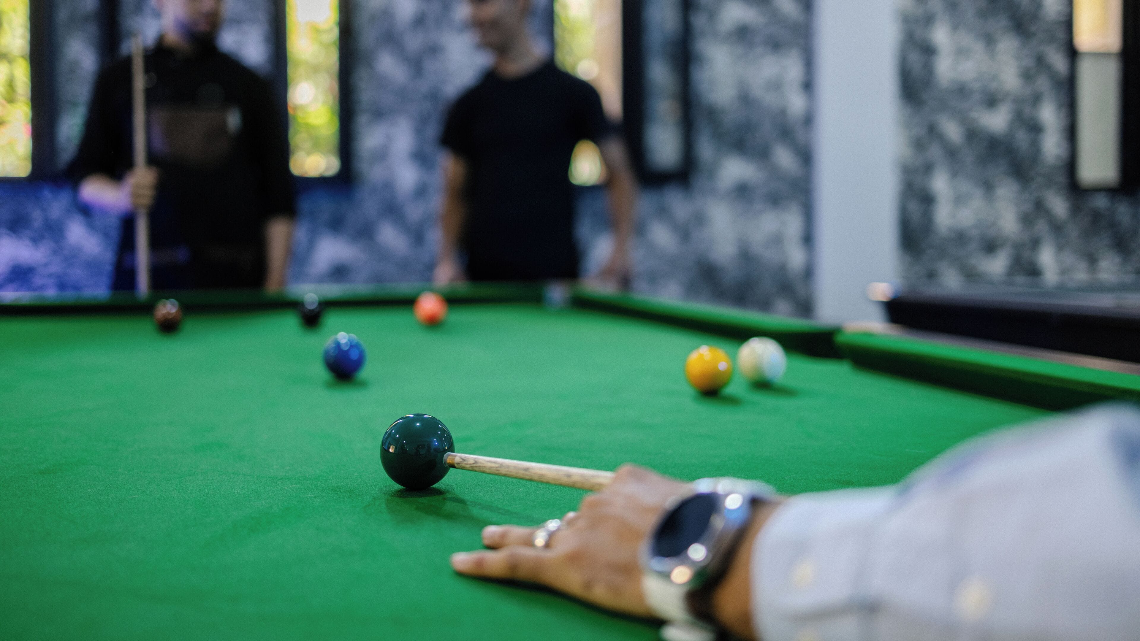 A pool table with balls and a cue stick.