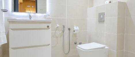 A modern bathroom with a white sink, mirror, and toilet.