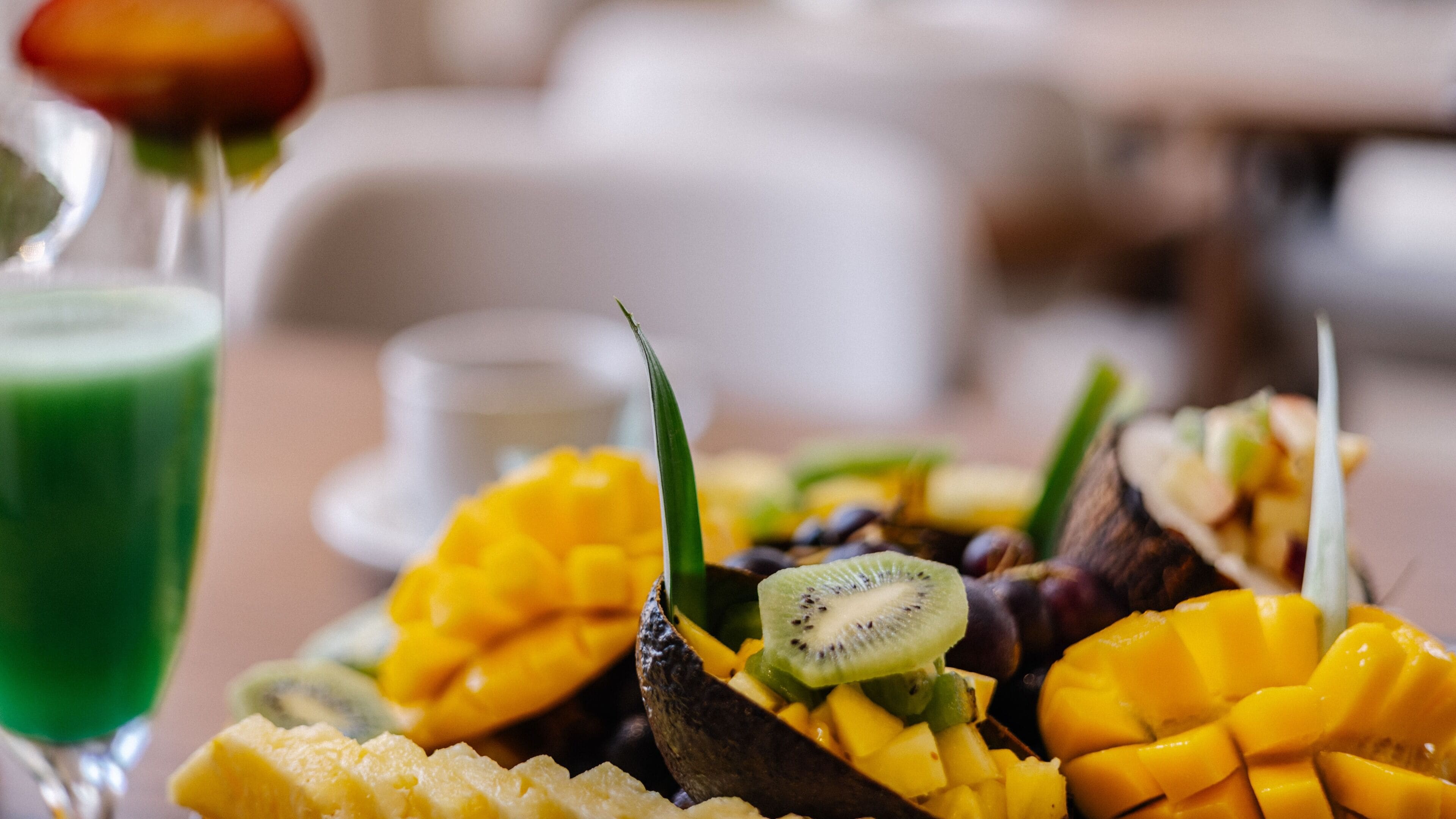 Una bandeja de frutas con mango, kiwi y otras frutas sobre una mesa.