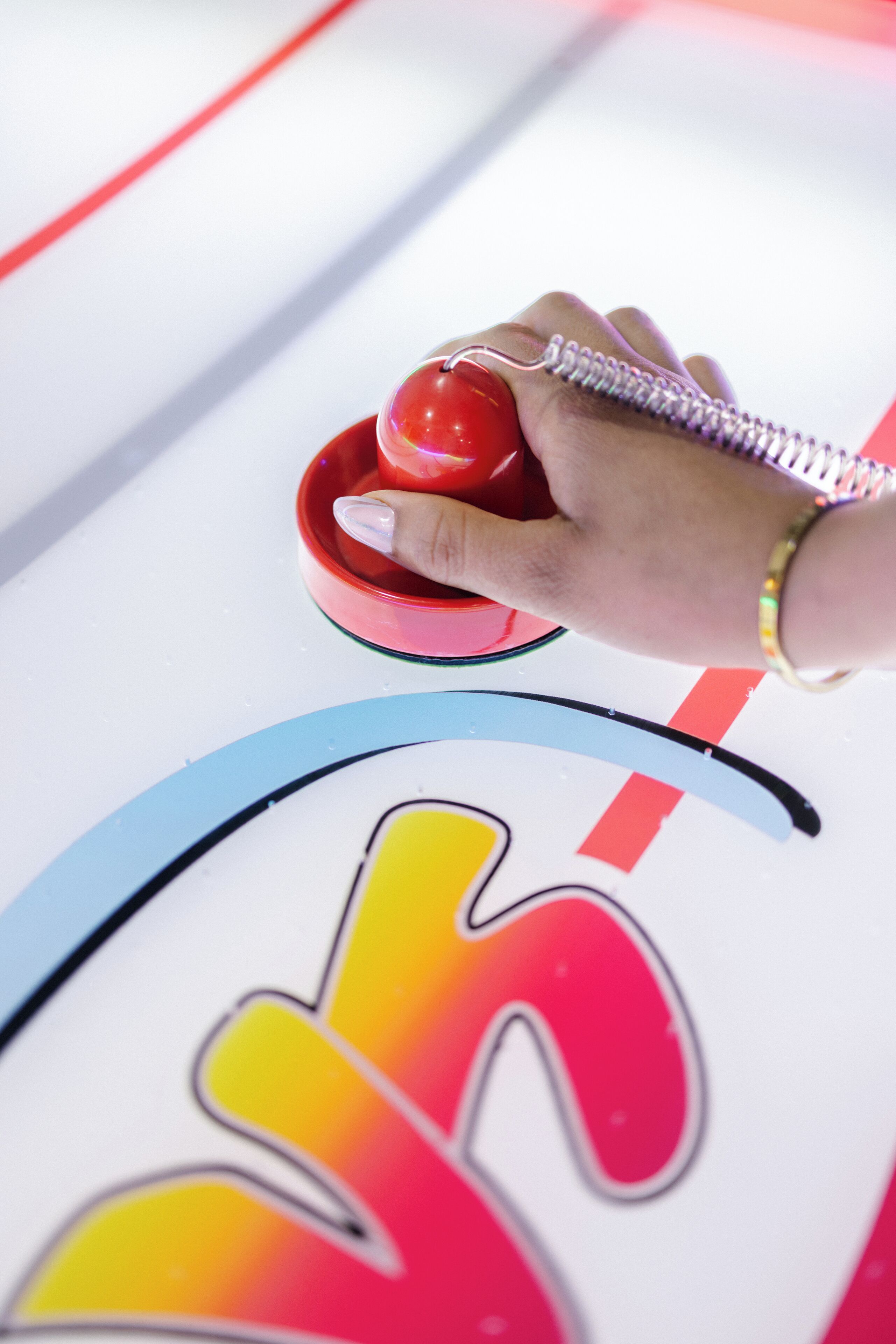 A hand holding a red object, possibly a toy or tool, over a colorful surface with a drawing of a person.