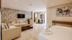 A modern hotel room with a marble floor, a sofa, a bed, a desk, and a TV mounted on the wall. - Hotel Prestige Agadir (Agadir)