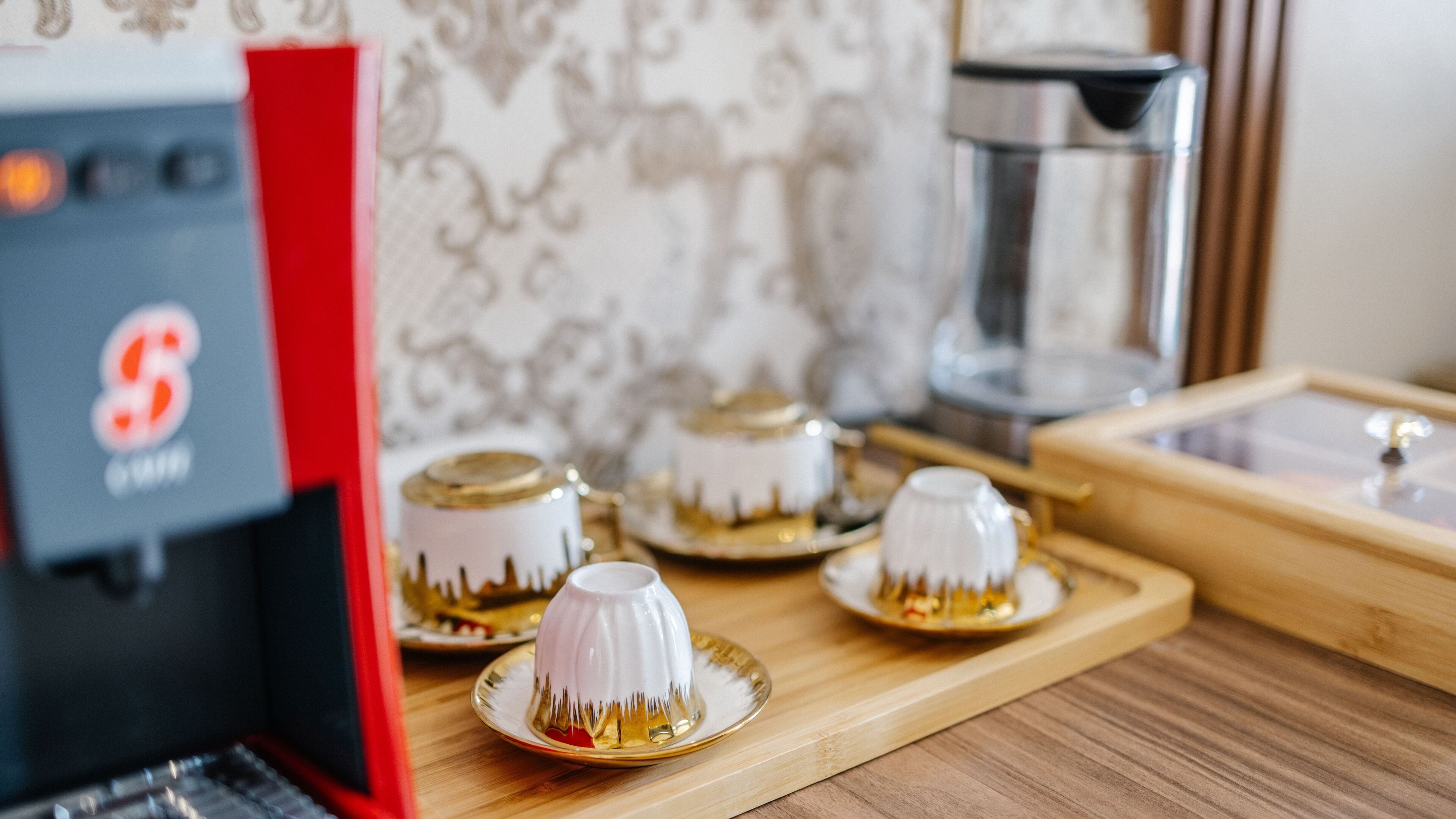 A coffee machine, a tea set, and a decorative plate on a wooden table.