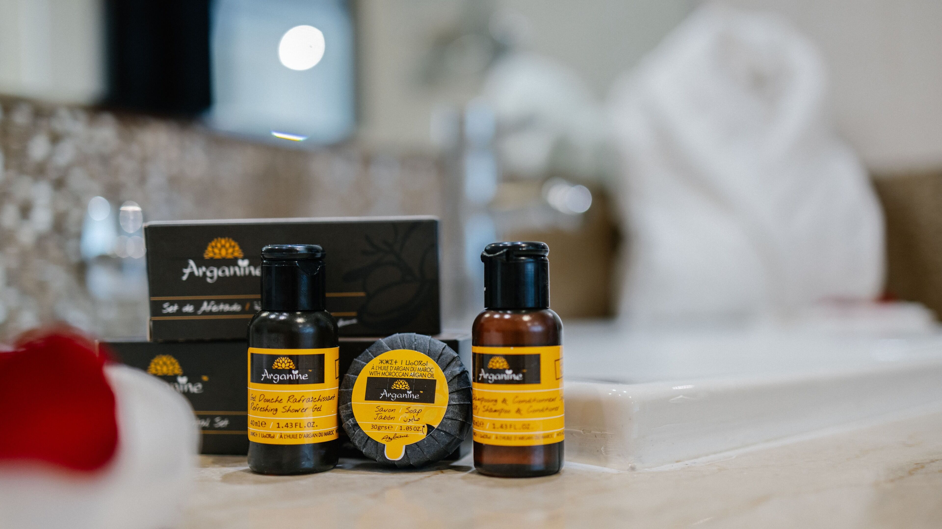 Three bottles of Arganine products on a bathroom counter.