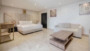 Una habitación de hotel moderna con una cama grande, un sofá, una mesa de centro y obras de arte en las paredes.