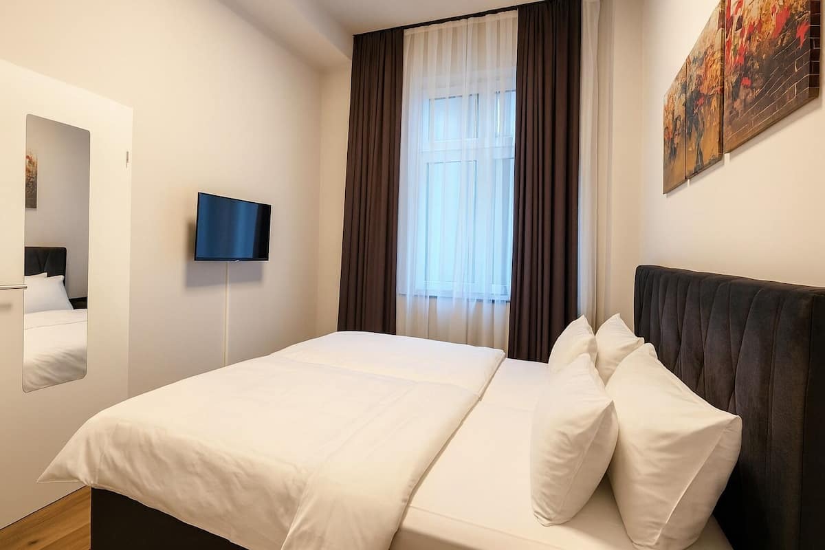 Ein Hotelzimmer mit einem großen Bett, einem flachbildfernseher an der Wand und einem Fenster mit Vorhängen.