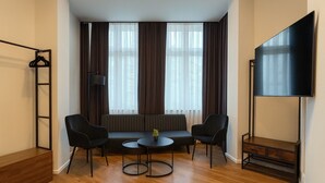 A modern room with a sofa set, a small round table, a TV, and a coat rack. - La Plaza24 (Düsseldorf)