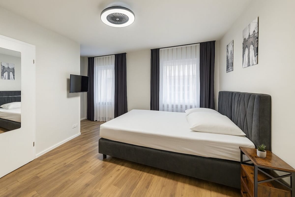 Ein modernes Hotelzimmer mit einem großen Bett, einem Flachbildfernseher und einem kleinen Tisch mit einer Pflanze.