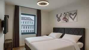 A hotel room with two beds, a TV, a window with curtains, and artwork on the wall. - La Plaza24 (Düsseldorf)
