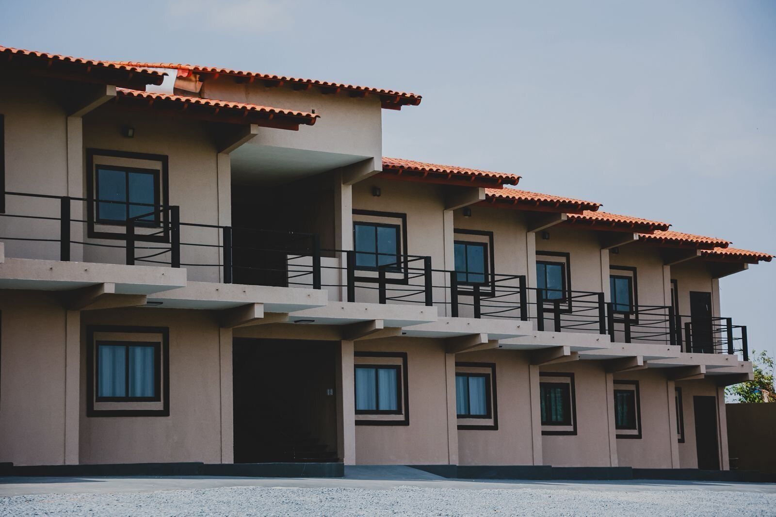 Un edificio de varios pisos con tejado plano, balcones y ventanas grandes.