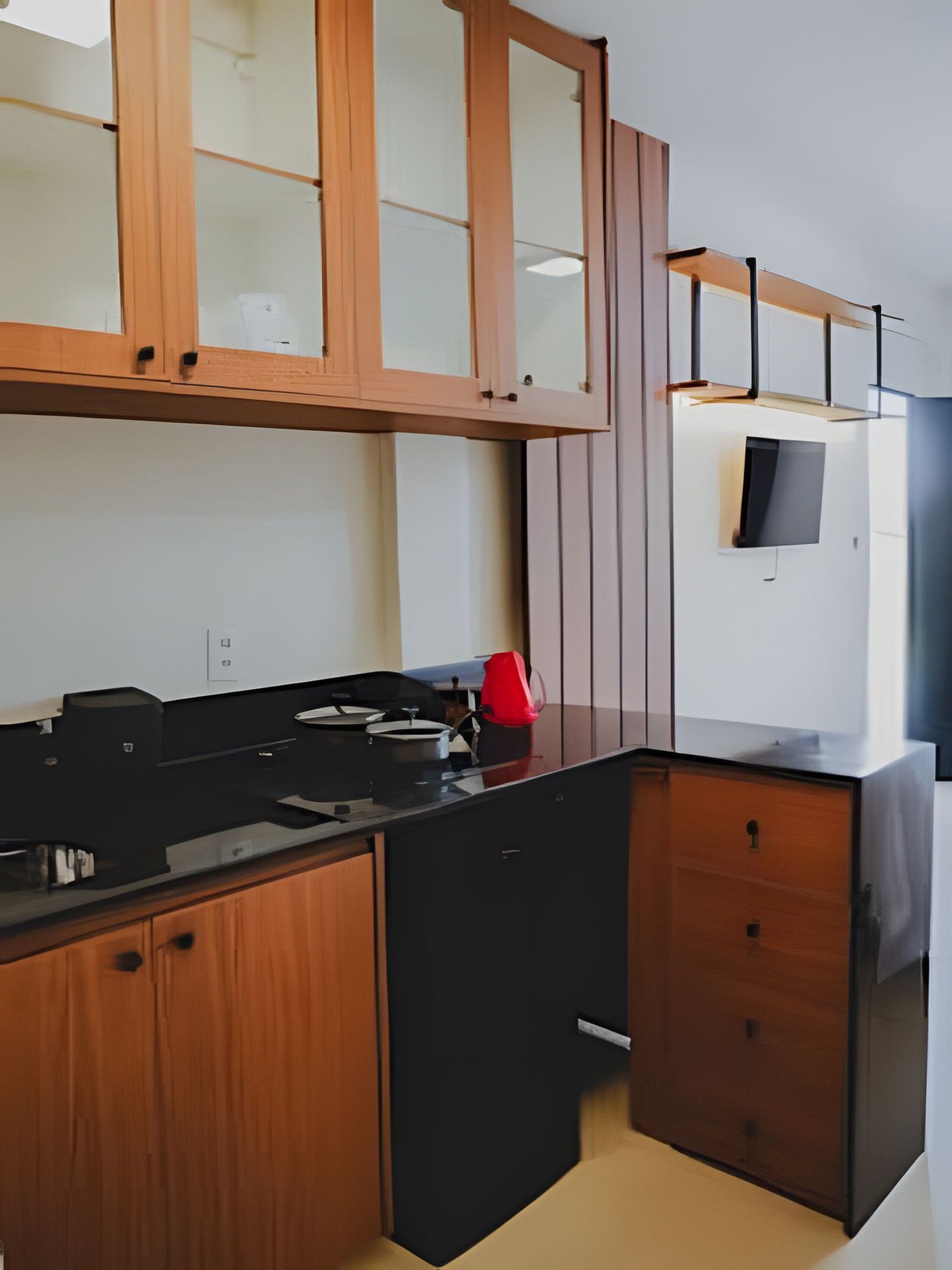 A modern kitchen with wooden cabinets, a black countertop, and a built-in stove.