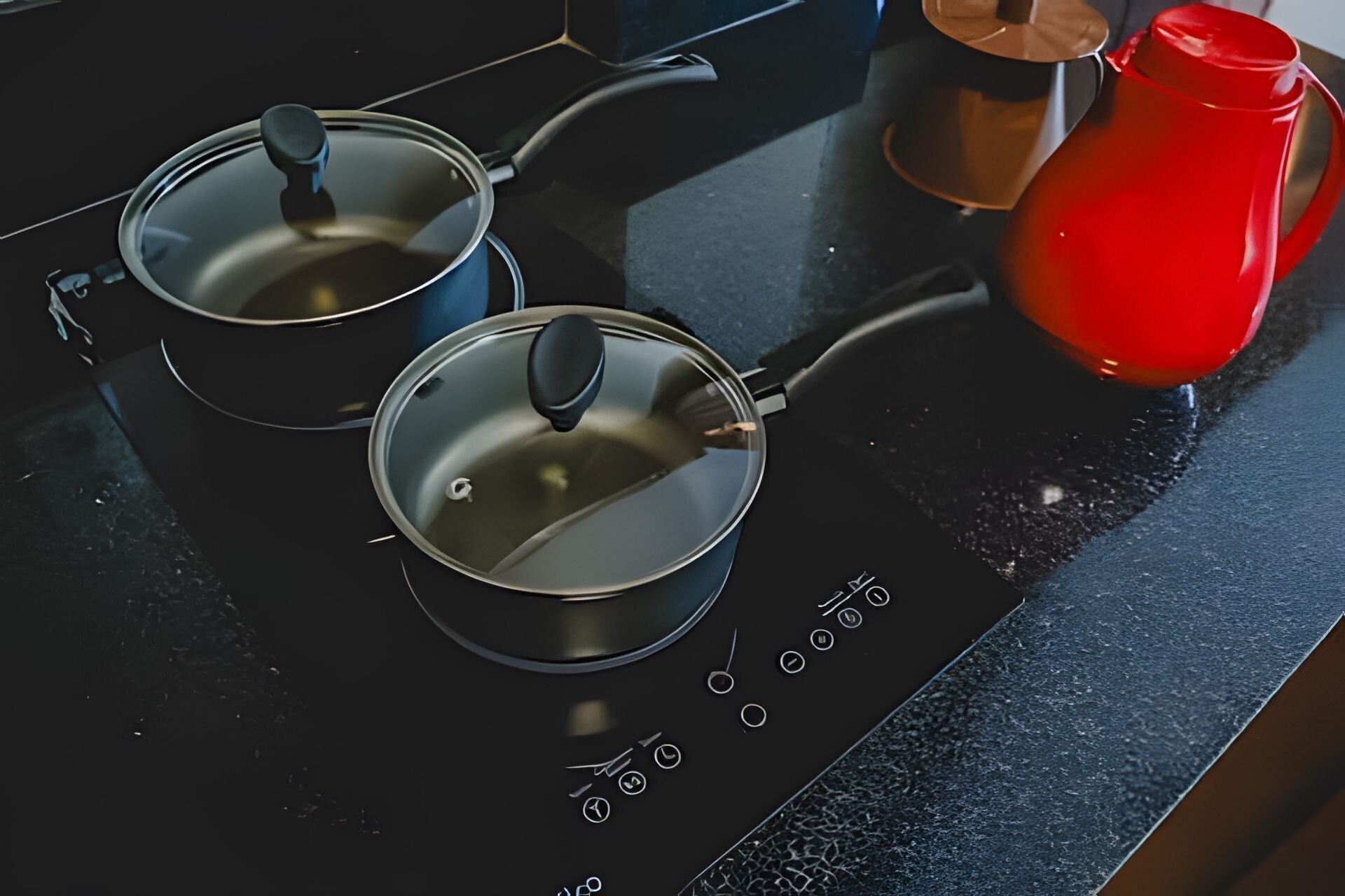 Una cocina con estufa, dos ollas y un hervidor rojo.