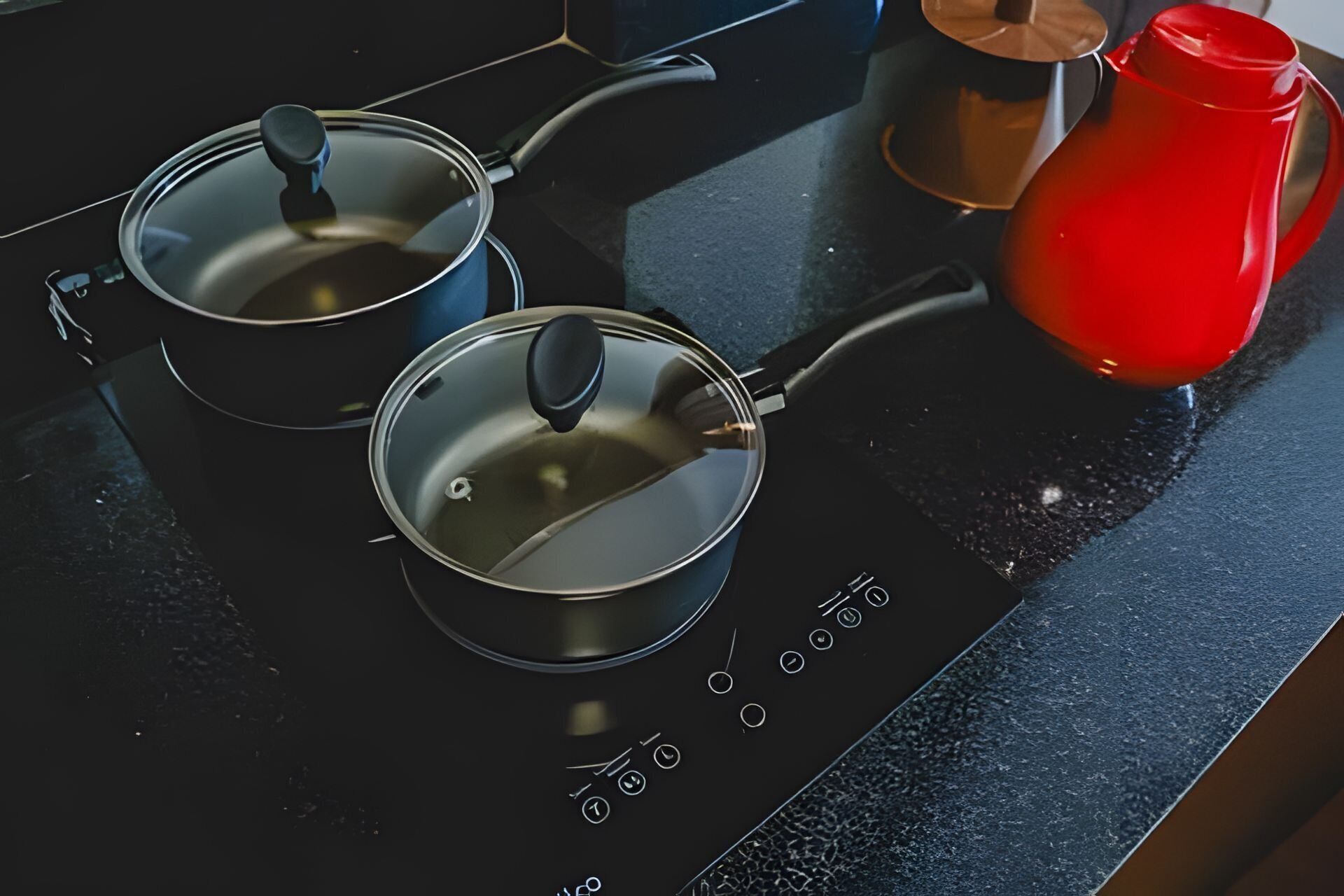 Tres ollas sobre una cocina negra con panel de control digital.