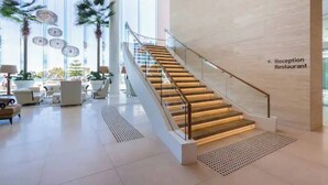A modern reception area with a staircase, seating, and a reception restaurant sign. - Absolute beachfront luxury in Surfers Paradise — a designer 3-bedroom apartment on level 11 of the iconic Peppers Soul tower. Panoramic ocean views, wraparound balcony, resort pools, spa & gym. Sleeps 6. Steps to the sand, 300m to Cavill Ave. (Surfers Paradise)