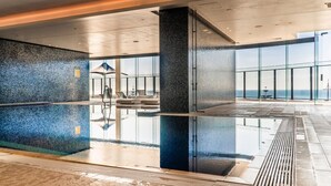 A modern indoor pool area with a glass wall offering a view of the sea. - Absolute beachfront luxury in Surfers Paradise — a designer 3-bedroom apartment on level 11 of the iconic Peppers Soul tower. Panoramic ocean views, wraparound balcony, resort pools, spa & gym. Sleeps 6. Steps to the sand, 300m to Cavill Ave. (Surfers Paradise)