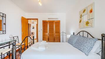Una camera da letto con un letto, un comodino, una lampada e un quadro appeso al muro.