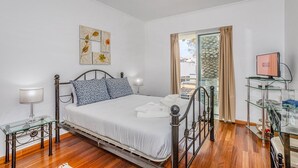 Un dormitorio con cama, mesitas de noche, televisor y obras de arte en la pared.