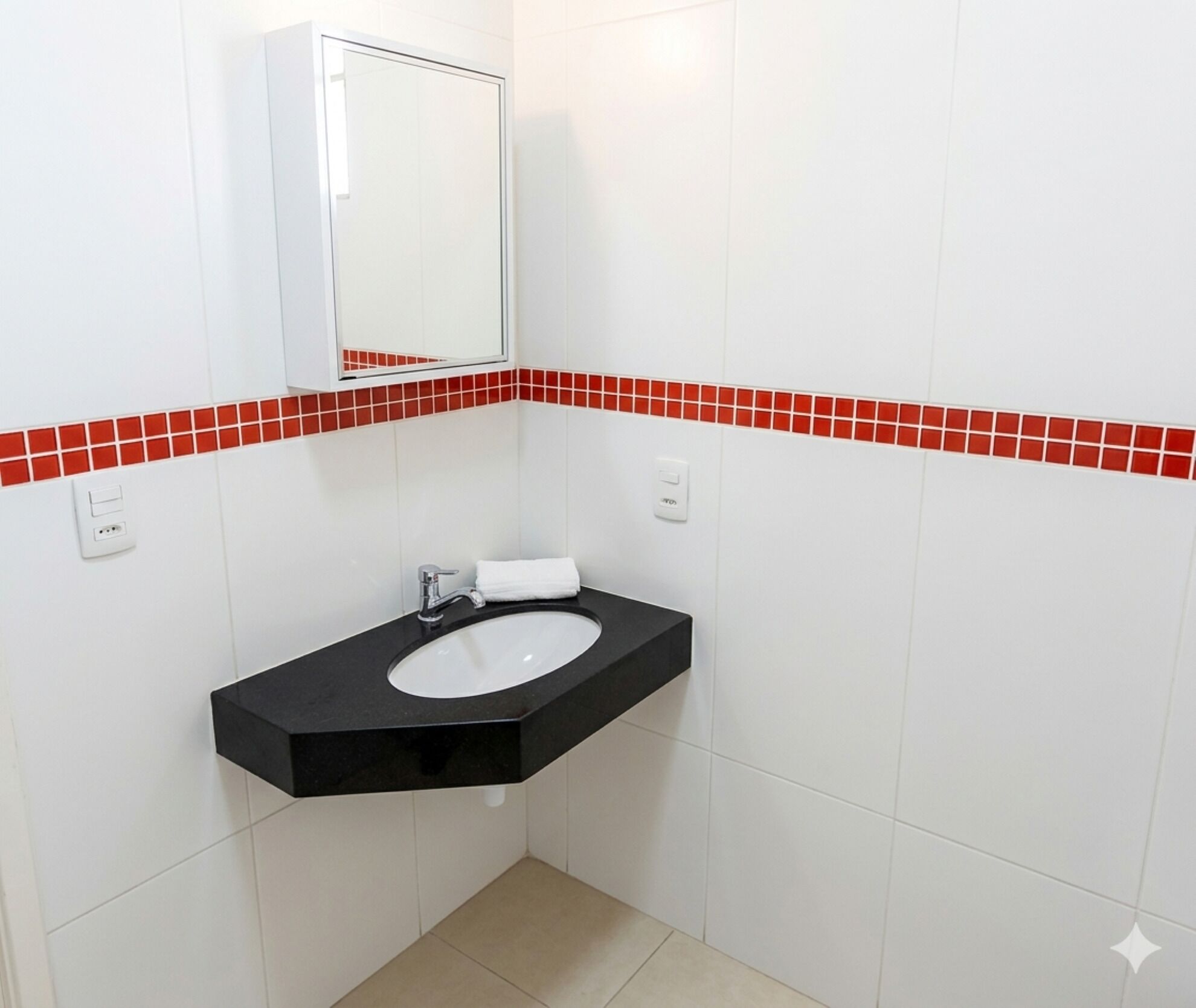 A bathroom with a black sink, white walls, and red-tiled accents.