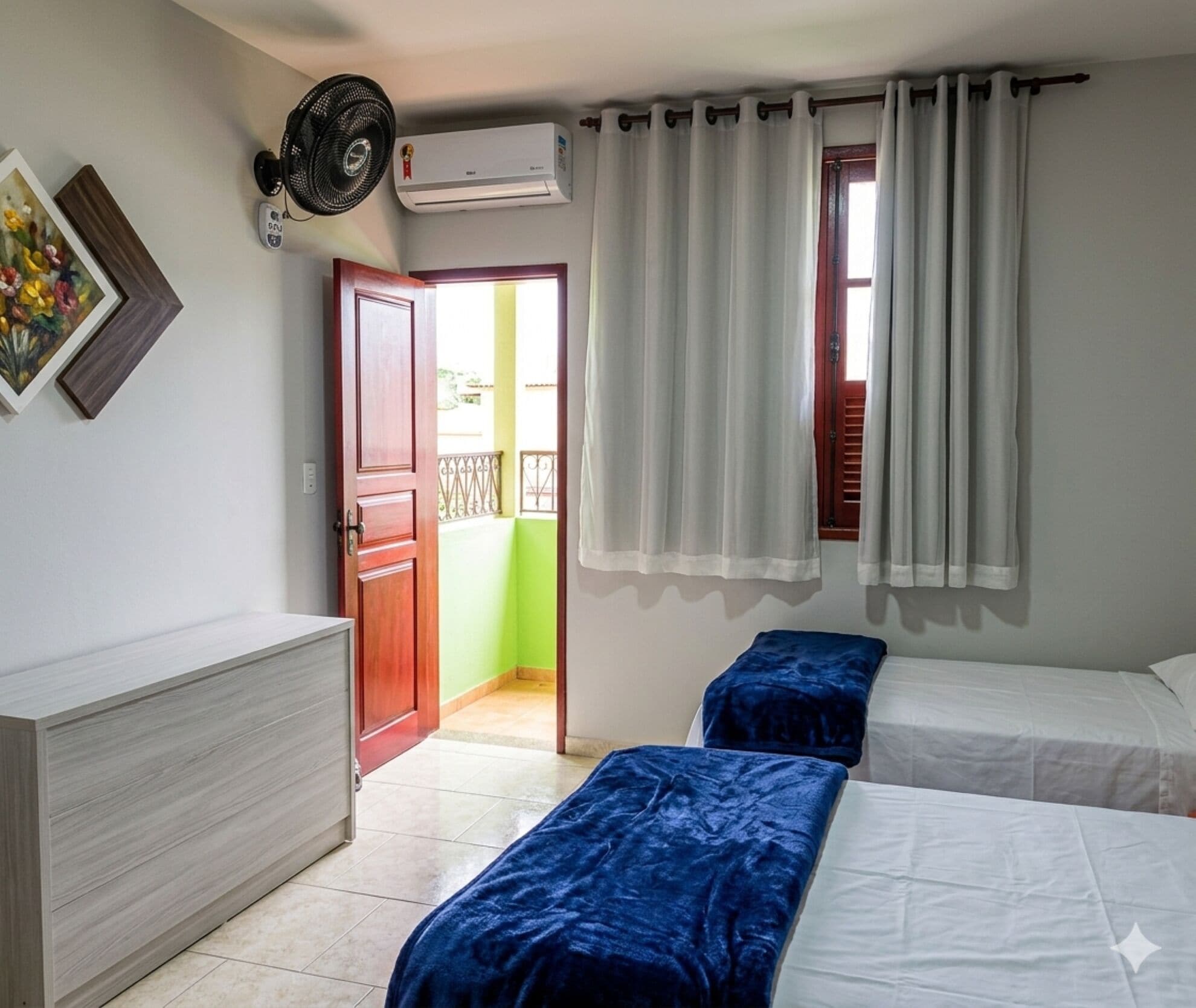Een slaapkamer met twee bedden, een houten garderobe, een plafondventilator en een airconditioning.