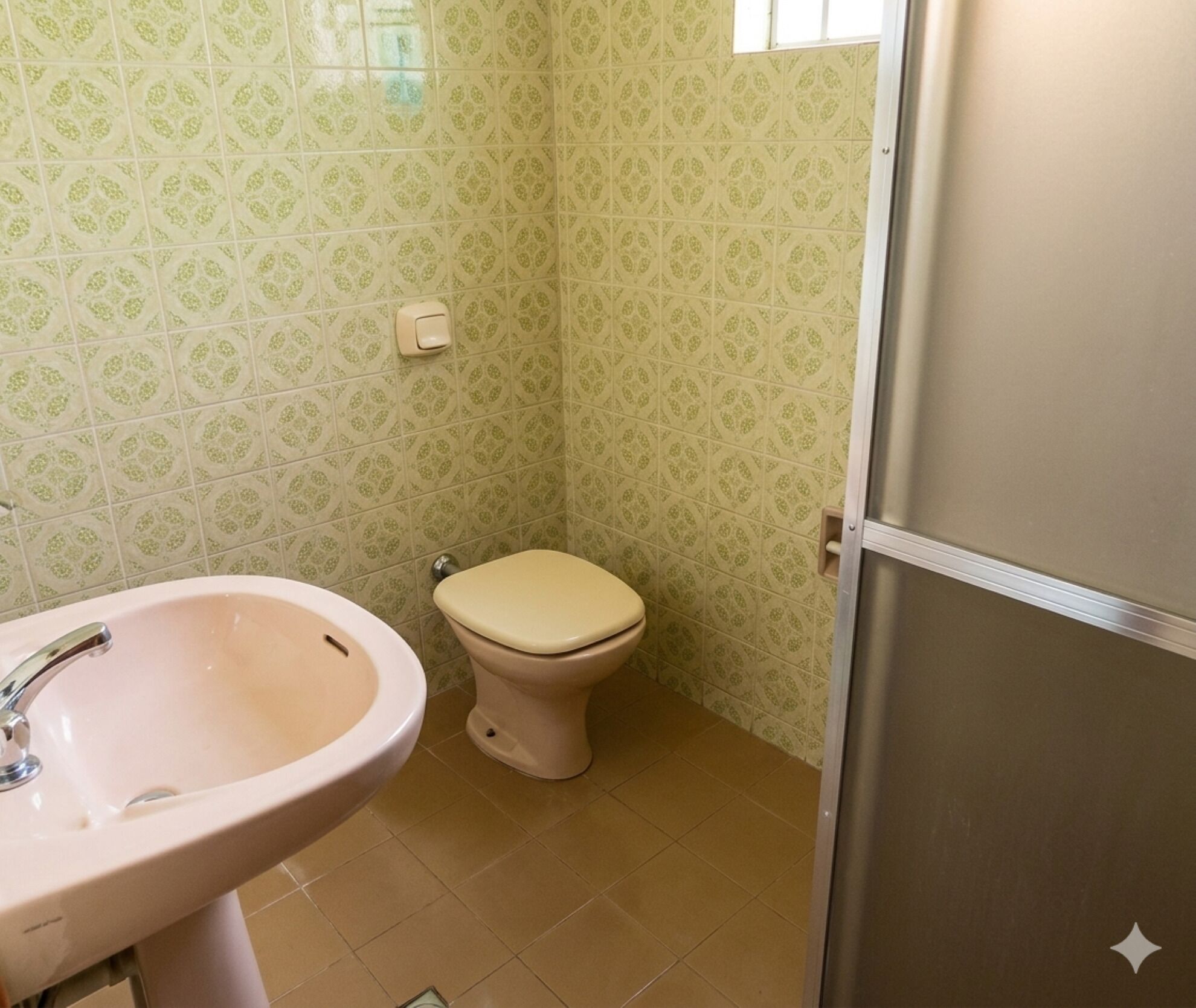 Casa de banho com lavatório, sanita, paredes com padrão e uma porta.