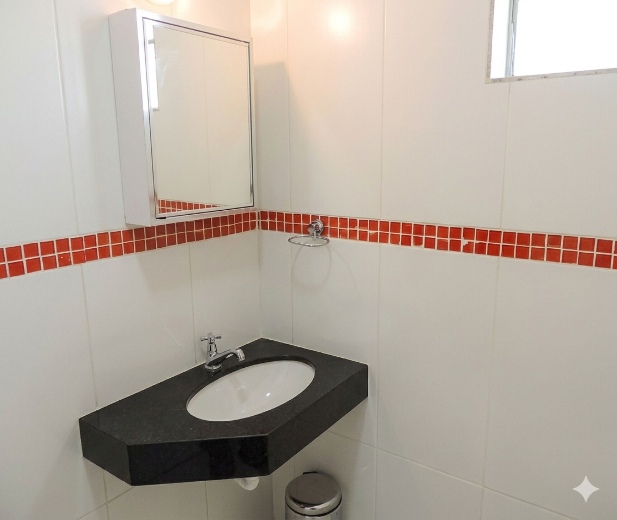 A bathroom with a black sink, a mirror, and red-tiled walls.