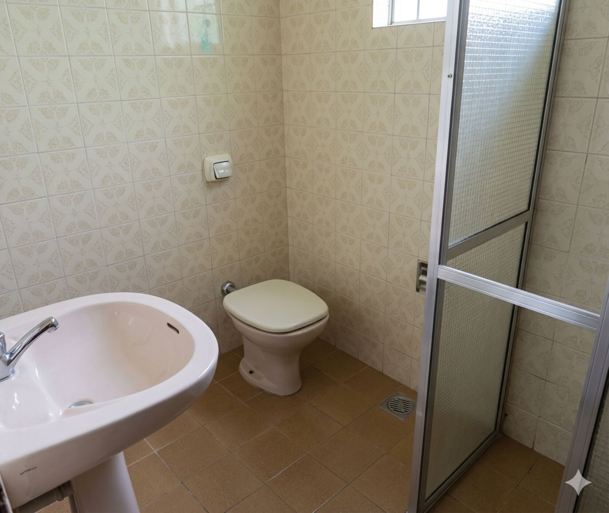 Un baño con lavamanos, inodoro y cabina de ducha de vidrio.