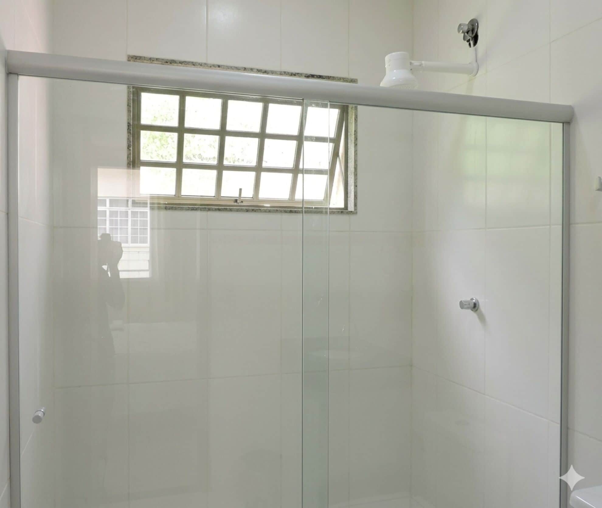 A glass-enclosed shower with a window, white tiled walls, and a visible hand dryer.