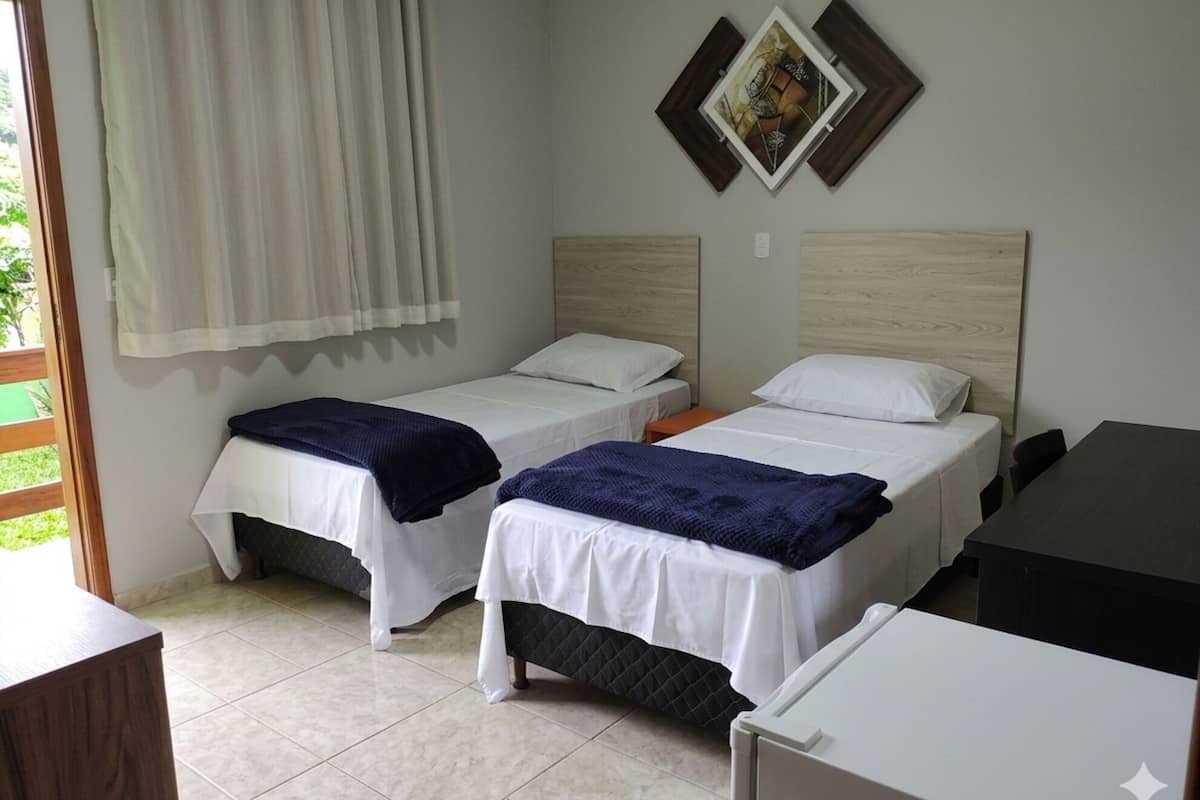 A hotel room with two beds, a desk, and a window with curtains.