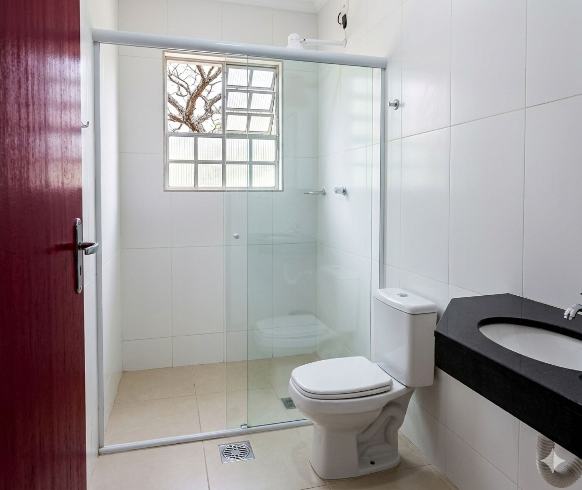 A bathroom with a glass-enclosed shower, a white toilet, and a black countertop sink.
