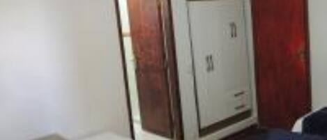 Habitación de hotel con una cama, un escritorio, un televisor montado en la pared y un armario.