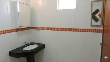 Casa de banho com lavatório preto, azulejos brancos e um espelho.