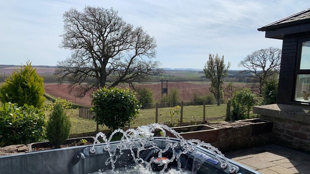 Un bain à remous offrant une vue sur un paysage rural, avec des champs et des arbres.
